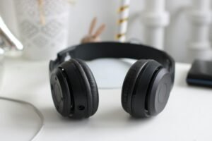 pexels-photo-815494-815494 Close-up of black wireless headphones on a white desk in a modern setting.
